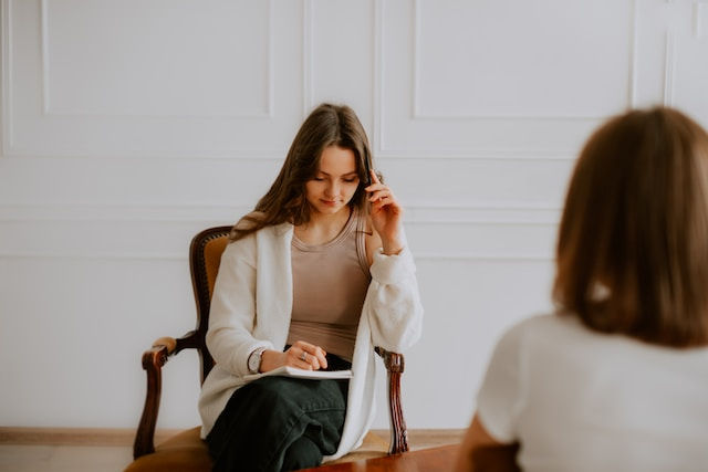 A woman sitting on chair looking down on her notebook