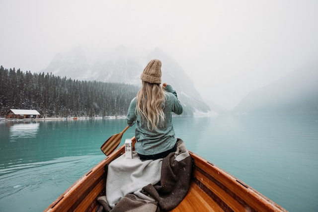 Woman sitting in brown wooden boat on lake