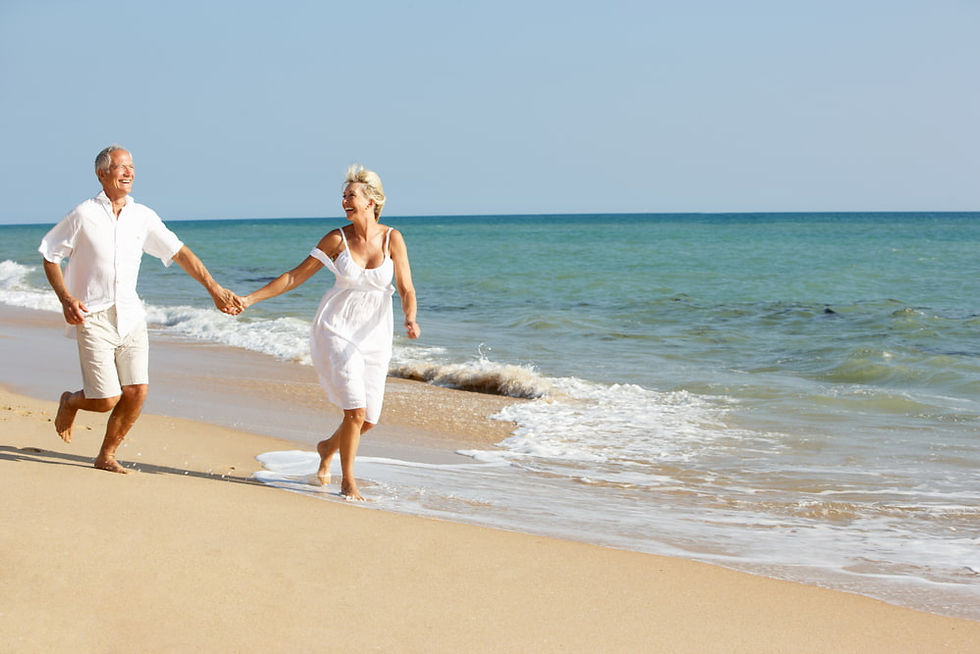 happy matured couple in white dress running at the beach