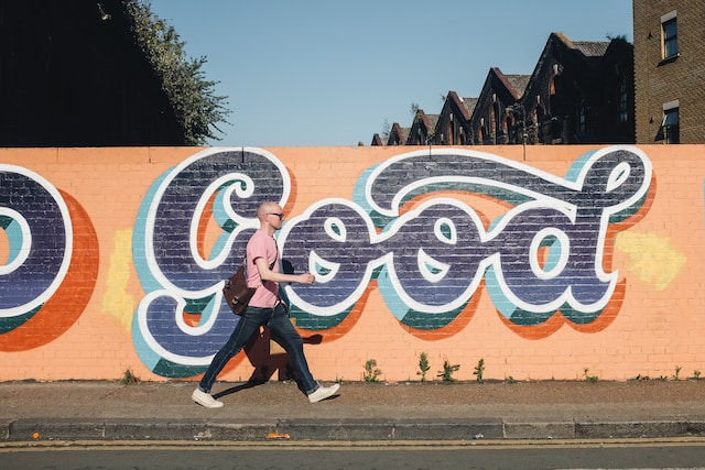 Man walking beside graffiti wall on a sunny day