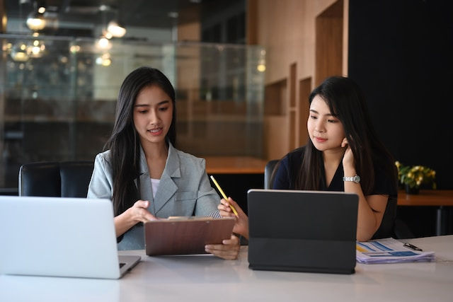 two women consulting using tablet and laptop