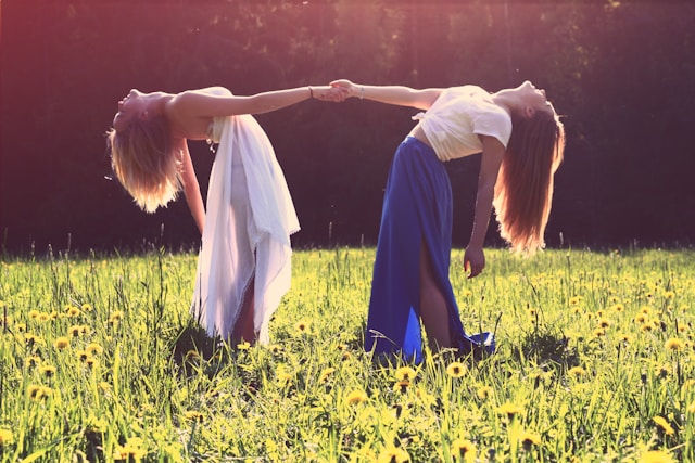 Two women bending while holding hands.