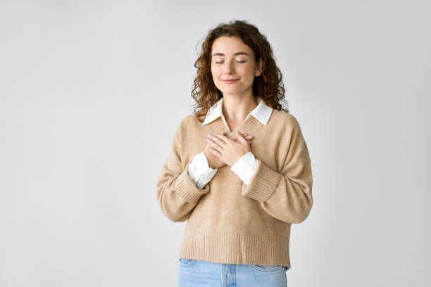 Happy pleased pretty young woman holding hands on chest feeling gratitude.