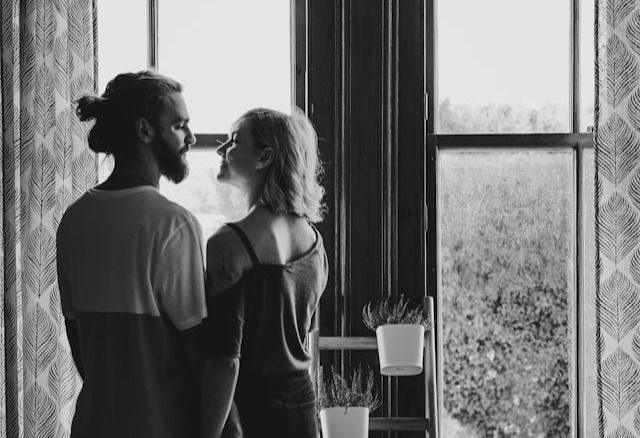 man and woman facing each other near window