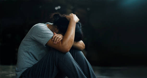 depressed woman sitting alone on the floor in the dark room background.