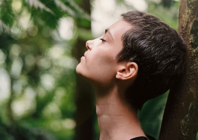 person leaning back on tree