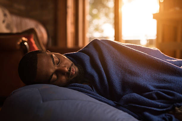 Tired man sleeping while being covered with blue blanket.