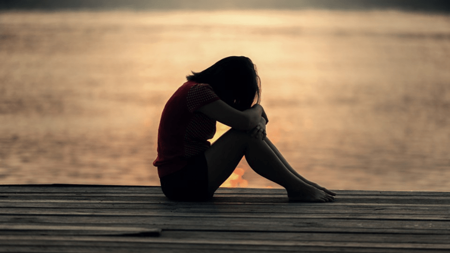 Woman sitting alone with her head on knee