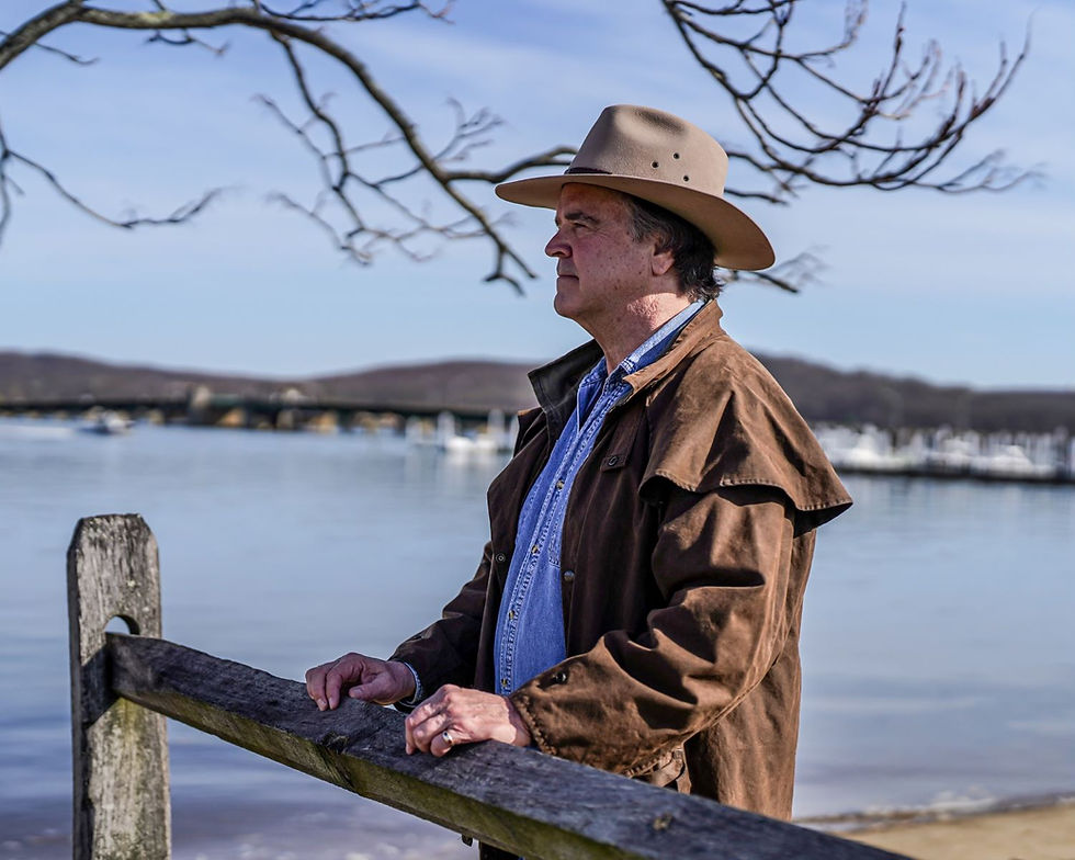 Man wearing cowboy hat standing near lake