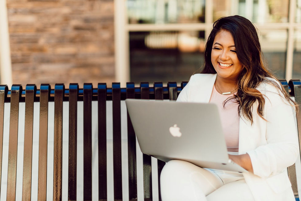 Photo of woman sitting outside the bench while using laptop
