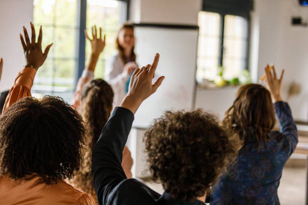  Businesswoman writing on whiteboard while holding a presentation for a group of business people