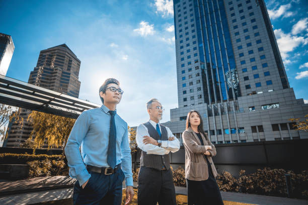 CEO and his team arms crossed standing at rooftop of office building in city during morning