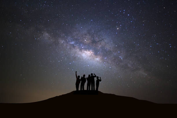 Starry night sky with stars and silhouette of people standing happy man on high mountain.