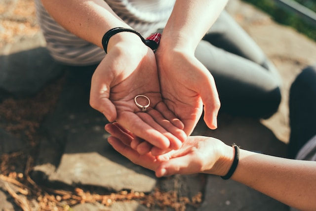 woman hands hold a gold ring with diamond