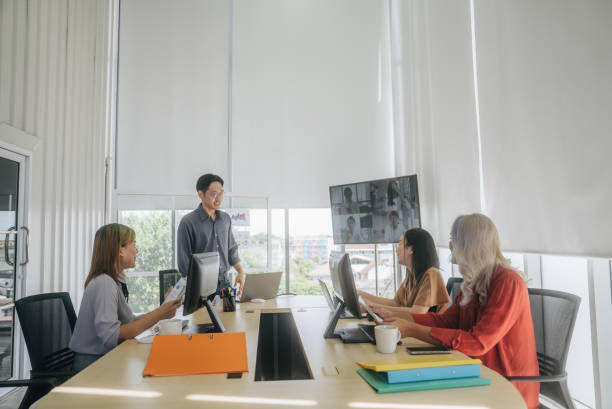 Group of people sitting and standing near the table conference using laptop.
