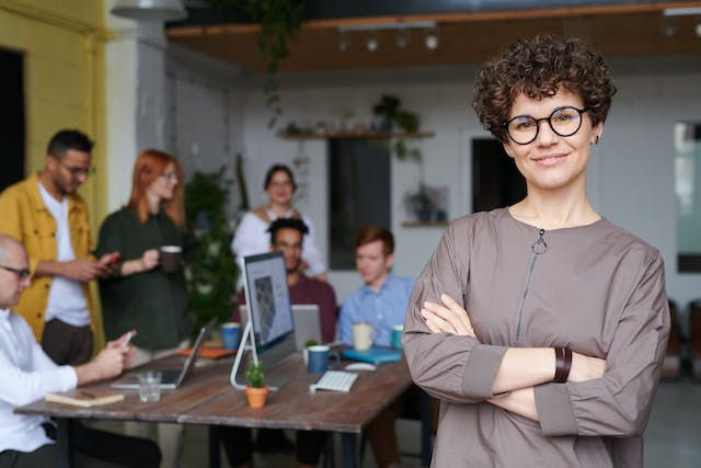 Photo of woman wearing eyeglasses and her team