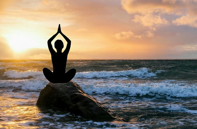 silhouette of a person meditating on rock near the sea shore