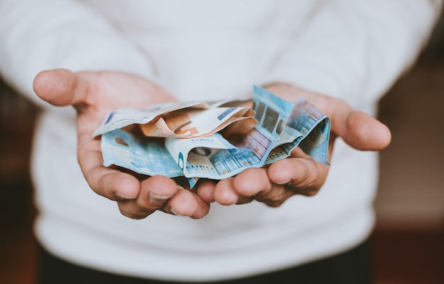 man in white sweater showing money on his palm
