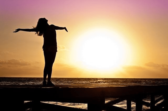 Silhouette of a woman spread arms near ocean