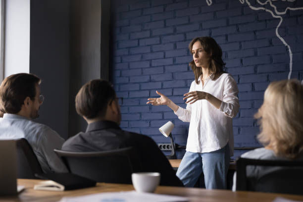 Serious pretty presenter girl speaking to coworkers, brainstorming on meeting