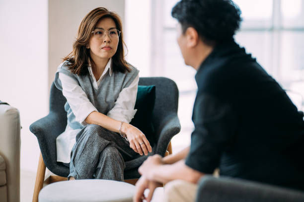 Female professional psychologist and a mature man are sitting on a cozy sofa.