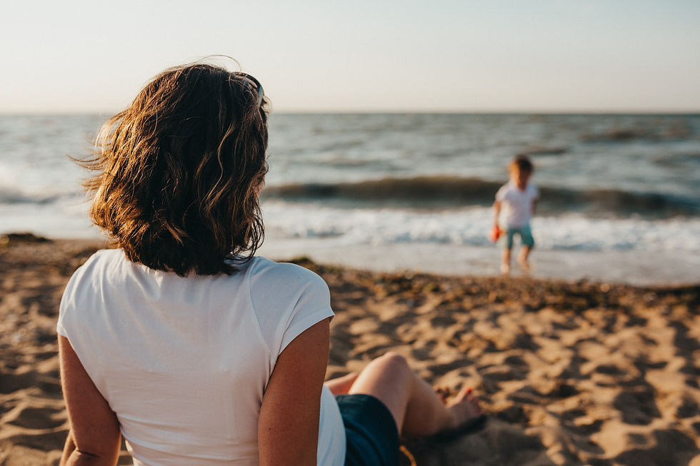 A mother watching her son playing at the beach.
