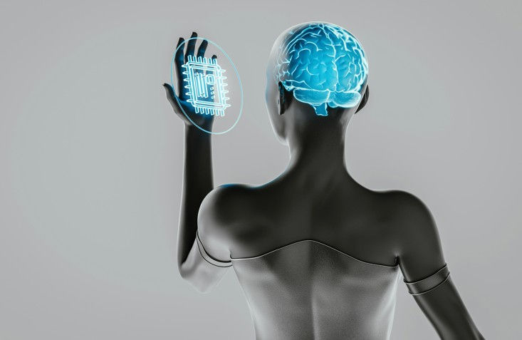 Futuristic humanoid with visible brain touches glowing microchip hologram against a gray background, symbolizing AI and technology.