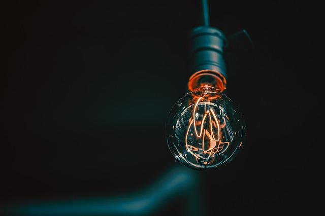 A clear light bulb hanging with a dark background.