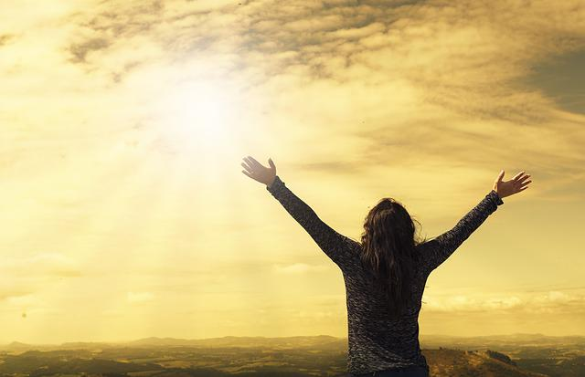 A woman looking and raising her hands up in the sky.