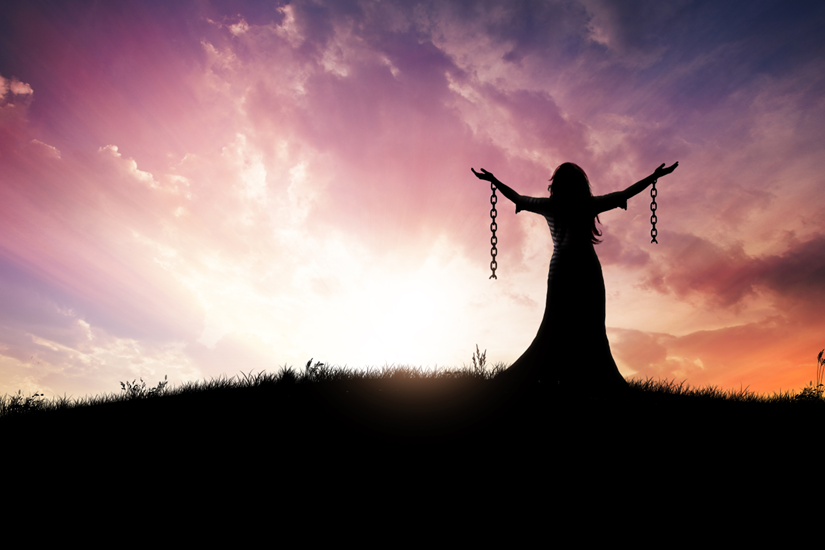 Free woman with chain, spreads her arms on a beautiful sunset.