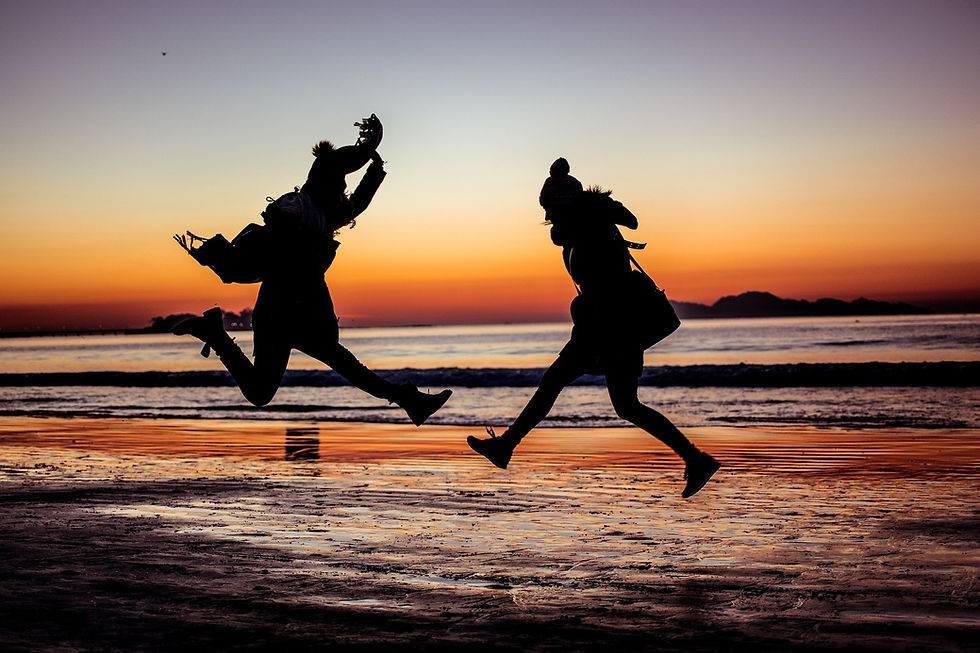 jump shot of two women at the beach during sunset.