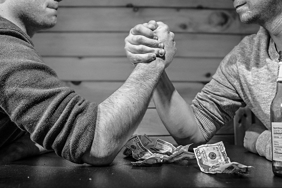 two men arm wrestling with money on the table in black & white photo. 
