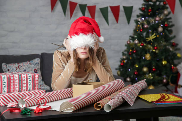 frustrated woman wrapping Christmas gift boxes.