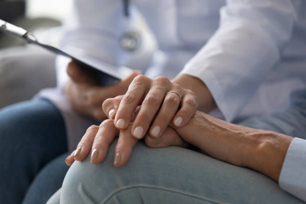 Young woman doctor holding hand of senior grandmother patient