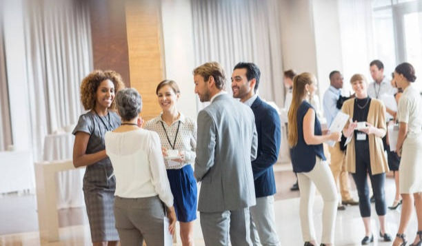 Group of business people standing in hall, smiling and talking together.
