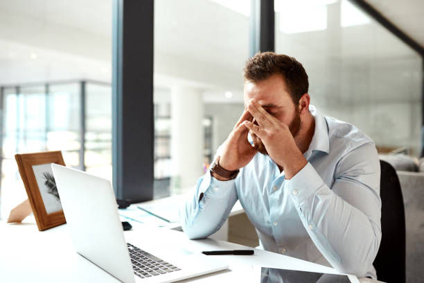 Shot of a young businessman looking stressed out while working in an office