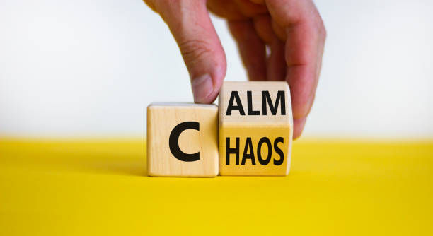 Male hand turns a wooden cube and changes the word 'chaos' to 'calm'.