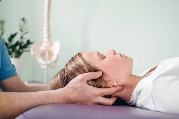 A woman lying down with a hand of another person performing a therapy