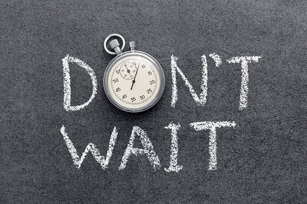 Don’t Wait phrase handwritten on chalkboard with vintage stopwatch. 