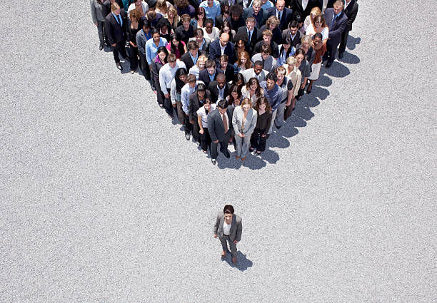 Crowd following a business woman outside, on sunny day.