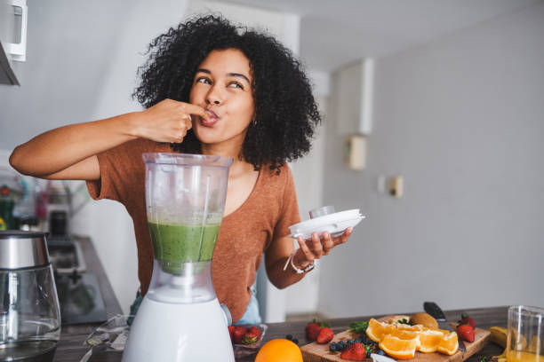 Shot of a young woman making a healthy smoothie at home.
