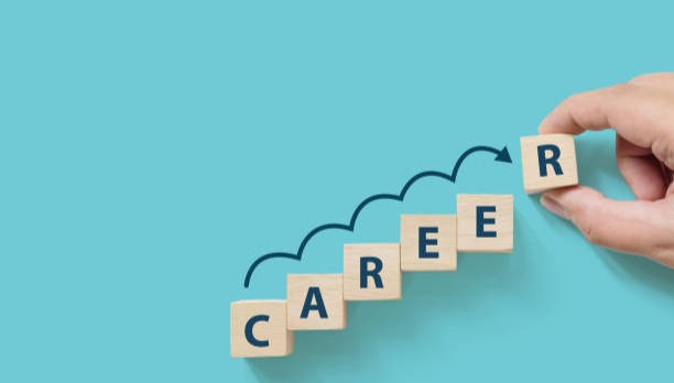 Hand putting wooden cube block on blue background with word CAREER.