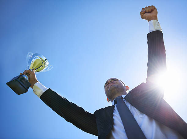 businessman holding a trophy on a sunny day.
