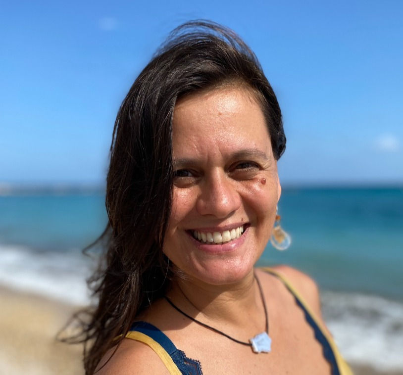 Shot of a woman at the beach smiling at camera.