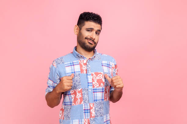 man with beard in blue shirt pointing himself,