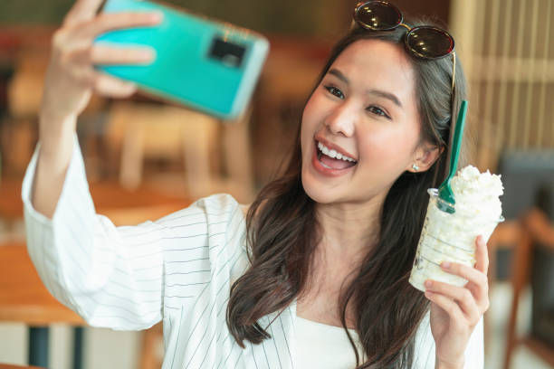 smiling  woman taking selfie while eating whipped cream
