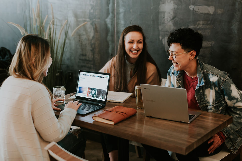 Three people having a fun moment with their laptops on the table.