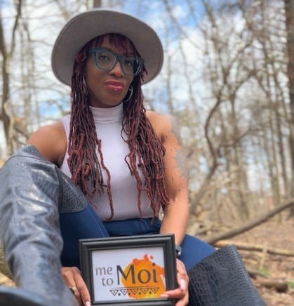 woman in eye glasses at the woods sitting on log holding a picture frame