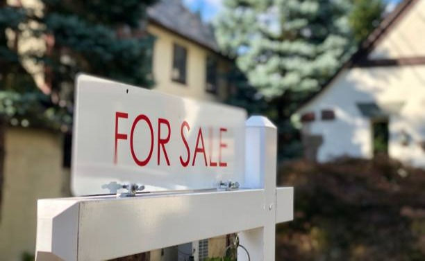 Real estate for sale sign in residential neighborhood.