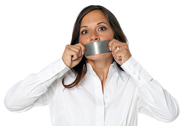 Woman in business attire can't talk because of the duct tape across her mouth.
